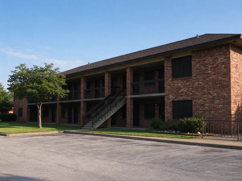 A two-story 1970s brick apartment building with an exterior upper walkway in Austin